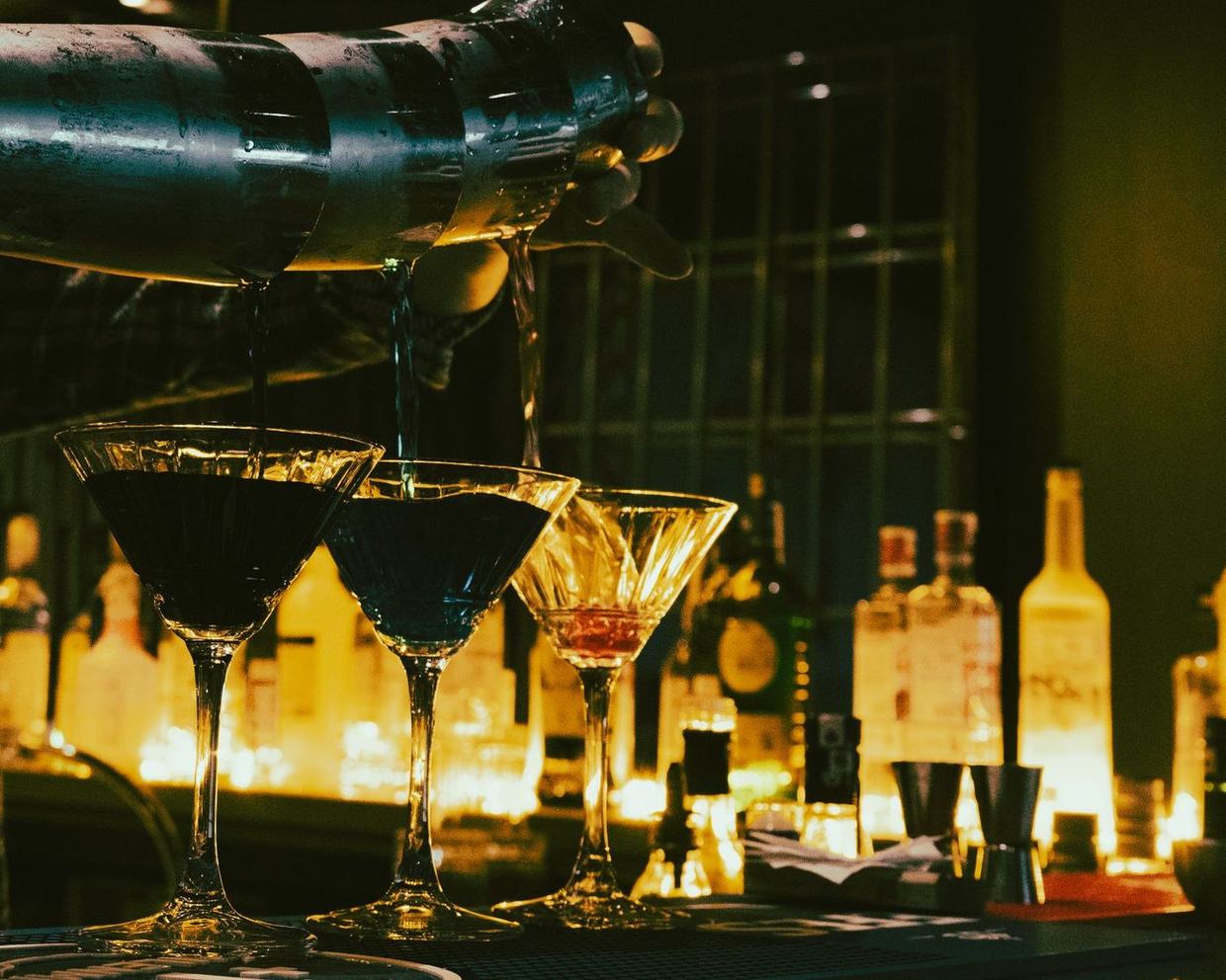 Cocktails being poured at a backlit bar