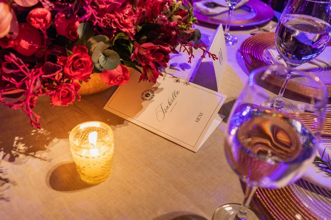 Candlelit place setting with flowers and a name card at a banquet